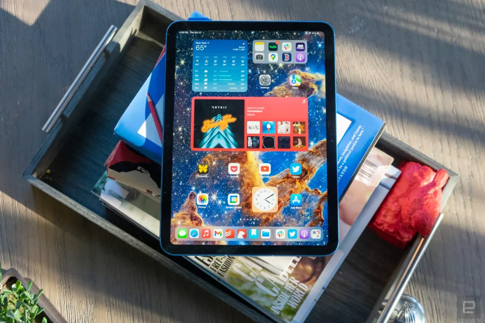 The tenth generation ipad sits on a pile of books. it looks pretty in the dapled afternoon sun.